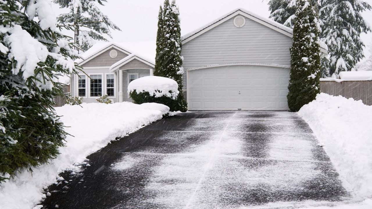 A new round of snow begins covering a recently shoveled driveway. Slow shutter speed to emphasize motion of the falling snow.