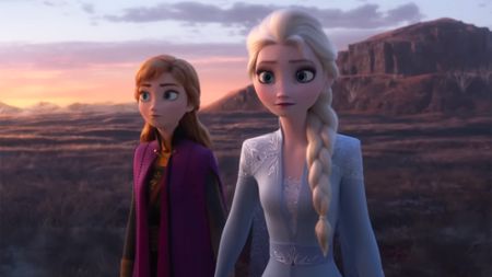 Anna and Elsa walk in a barren landscape in signature purple and lilac blue in Frozen 2 scene. 