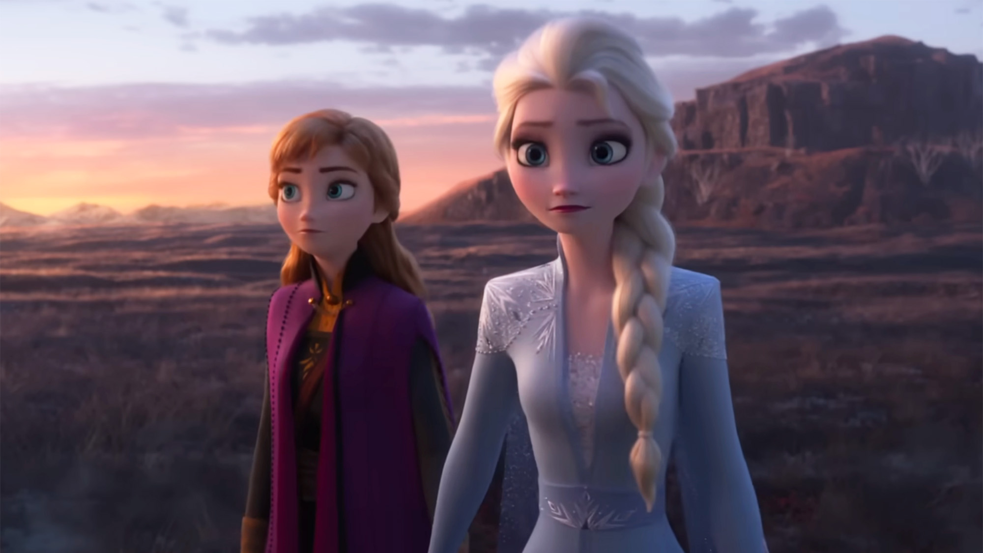 Anna and Elsa walk in a barren landscape in signature purple and lilac blue in Frozen 2 scene. 