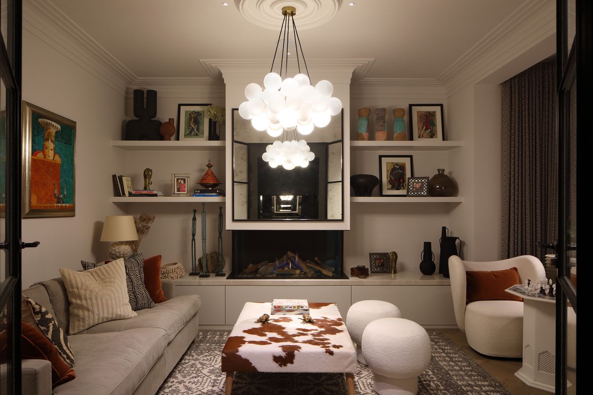A reception room with a statement ceiling lamp and recessed shelves with lighting