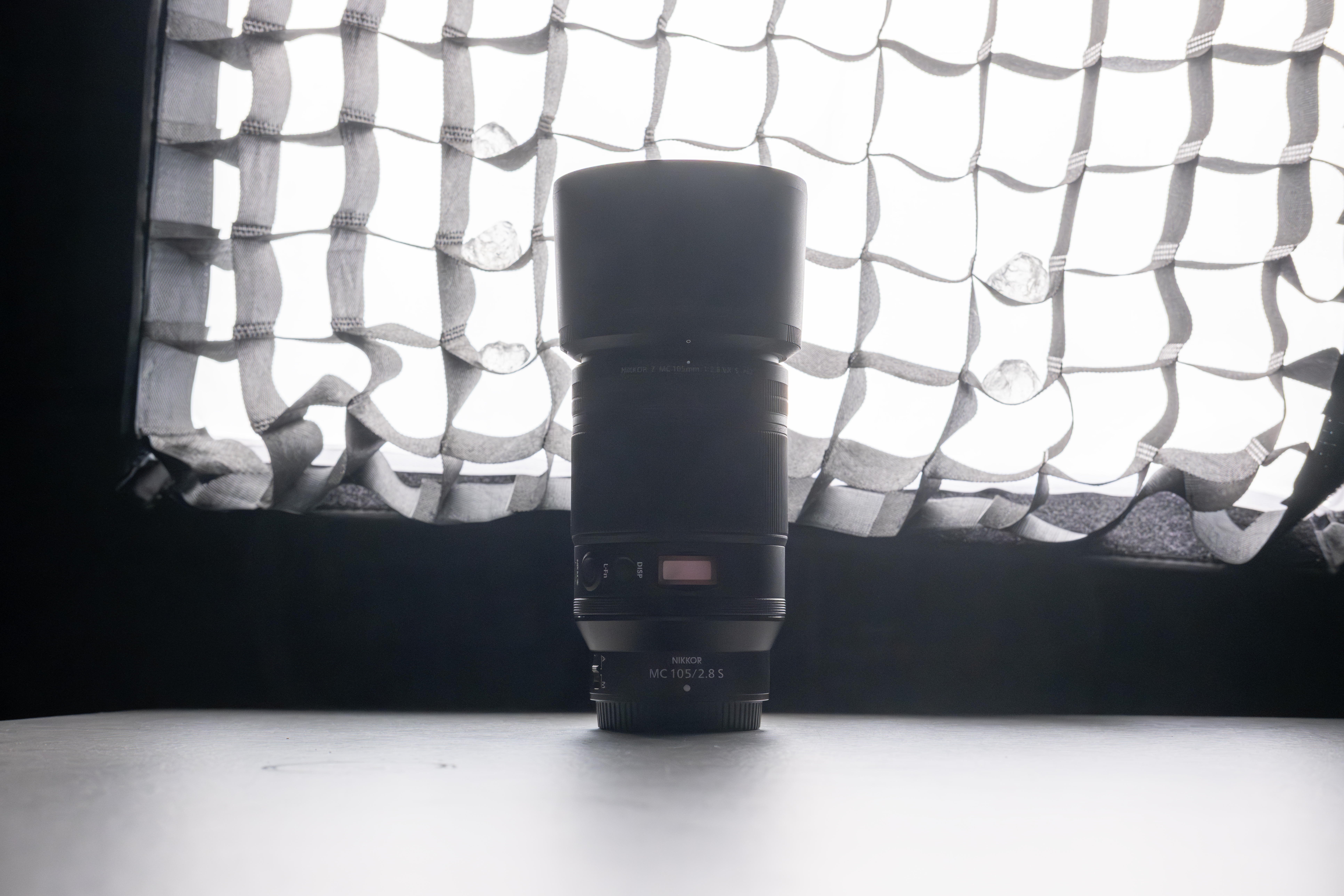 A backlit photo of a Nikon lens in front of a lit softbox, brightened in post production.