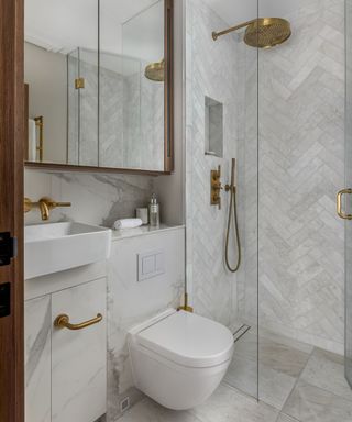 small bathroom decorated with marble tiles and gold hardware