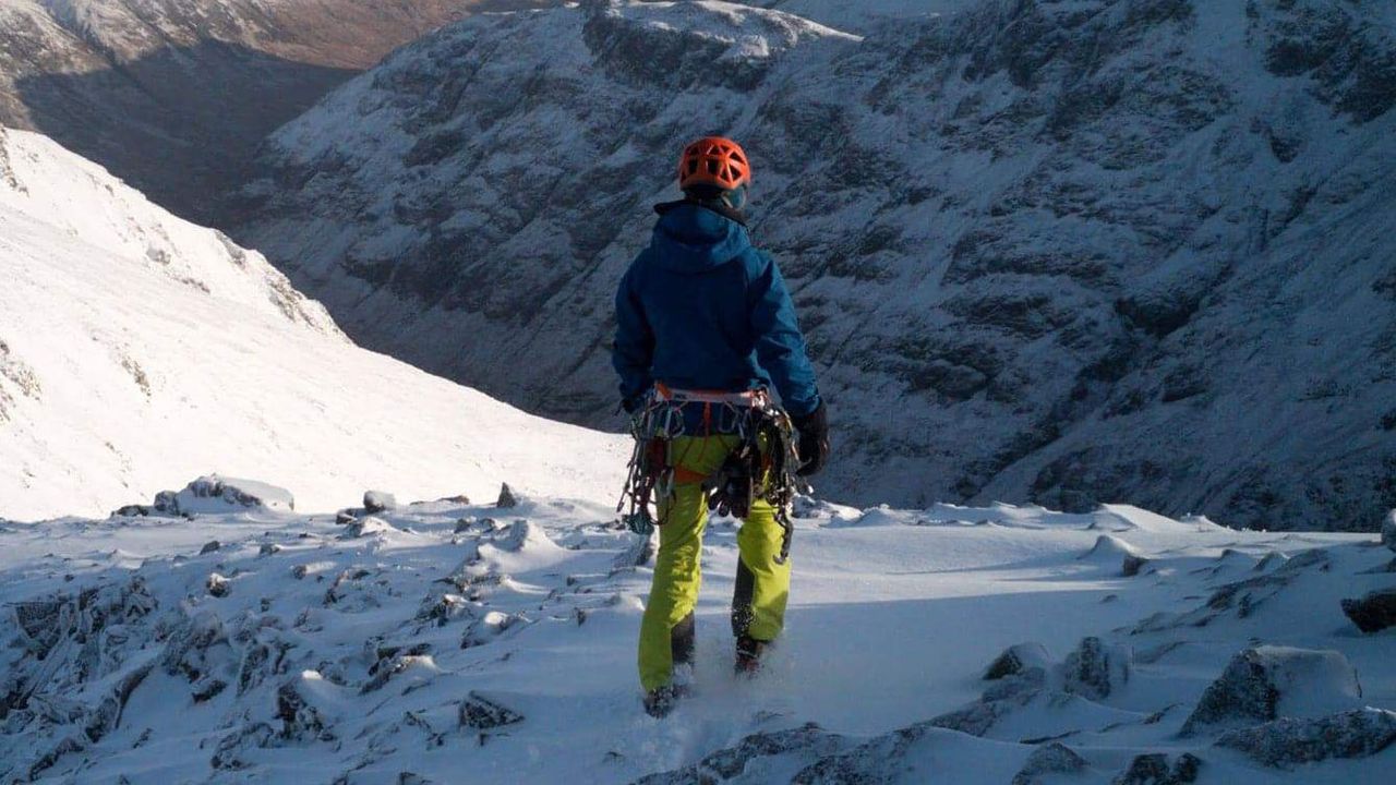 man wearing Jottnar Odin hardshell jacket in an alpine landscape