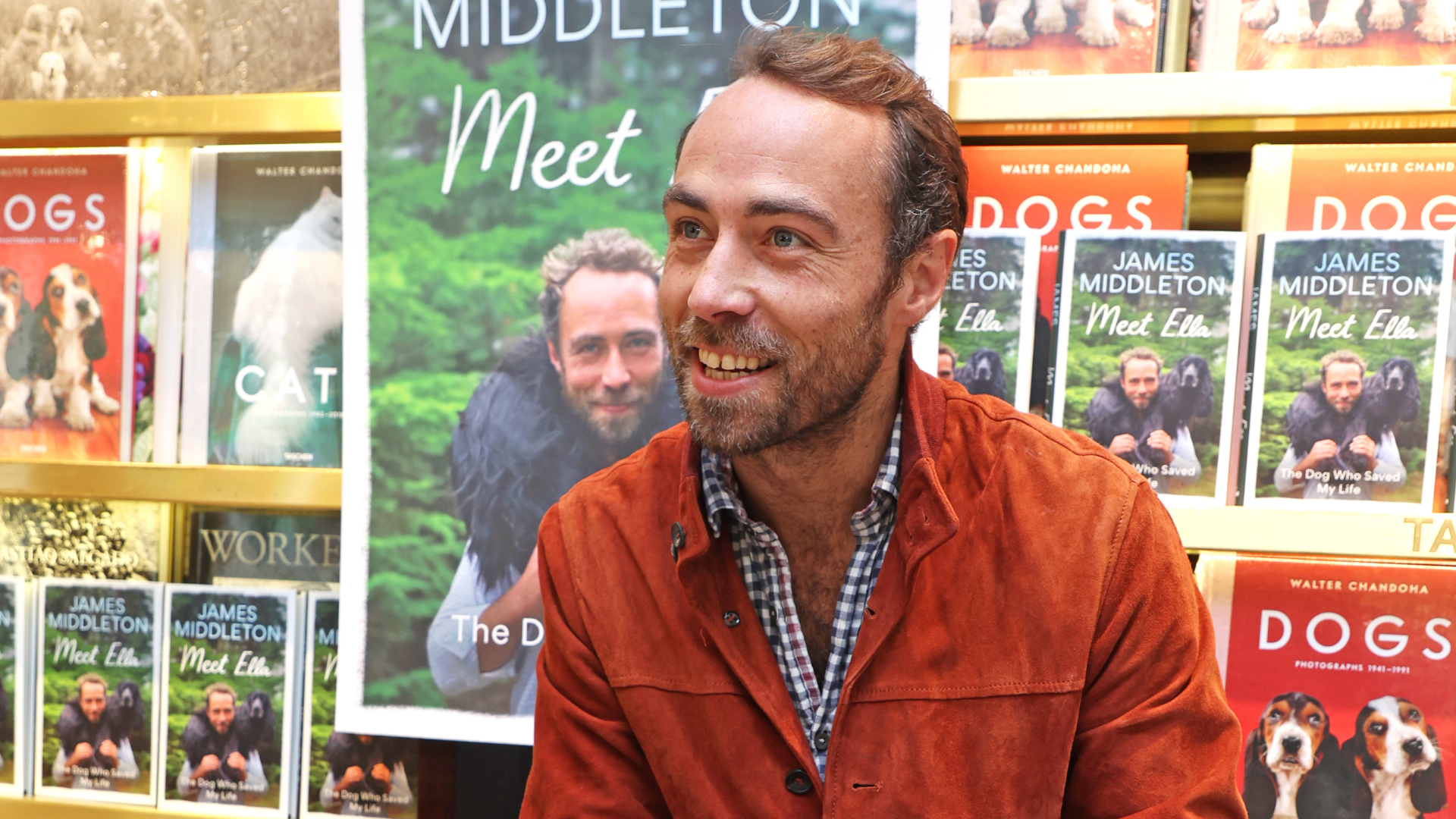 James Middleton sitting in front of a table of his memoir and bookshelves with dog books