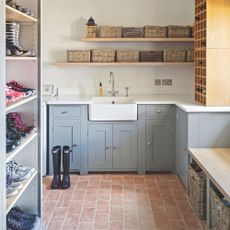 White painted boot room with blue cabinets and a white sink, and a large shoe rack on the left hand side 