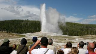 Tourists watching Old Faithful erupt at Yellowstone National Park