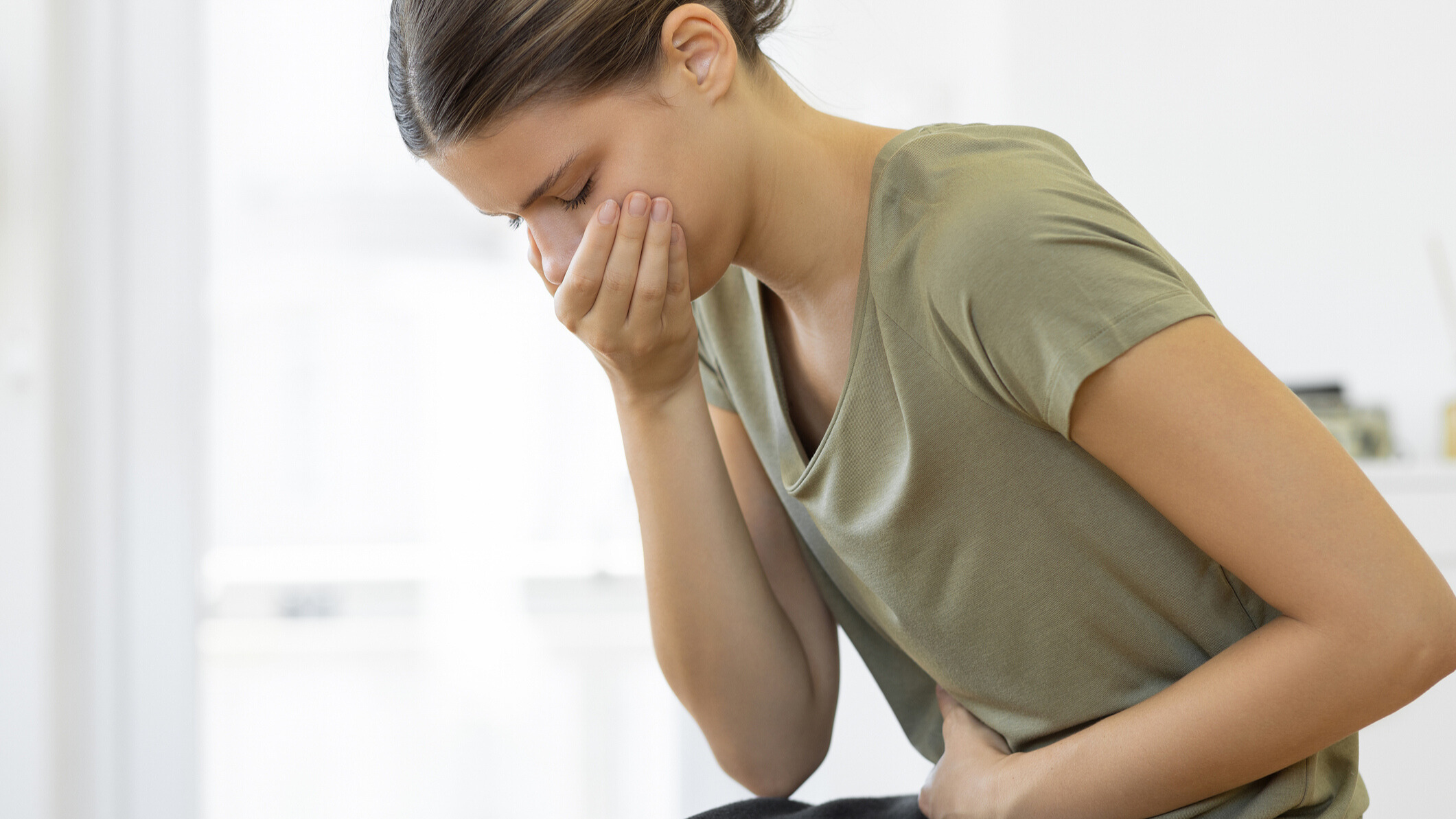 Woman holding her mouth and stomach stopping herself from vomiting