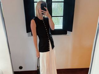 Natalie Cantell taking a mirror selfie in Menorca, wearing a white skirt and leather flip-flops from Mango and carrying a bag from Celine.