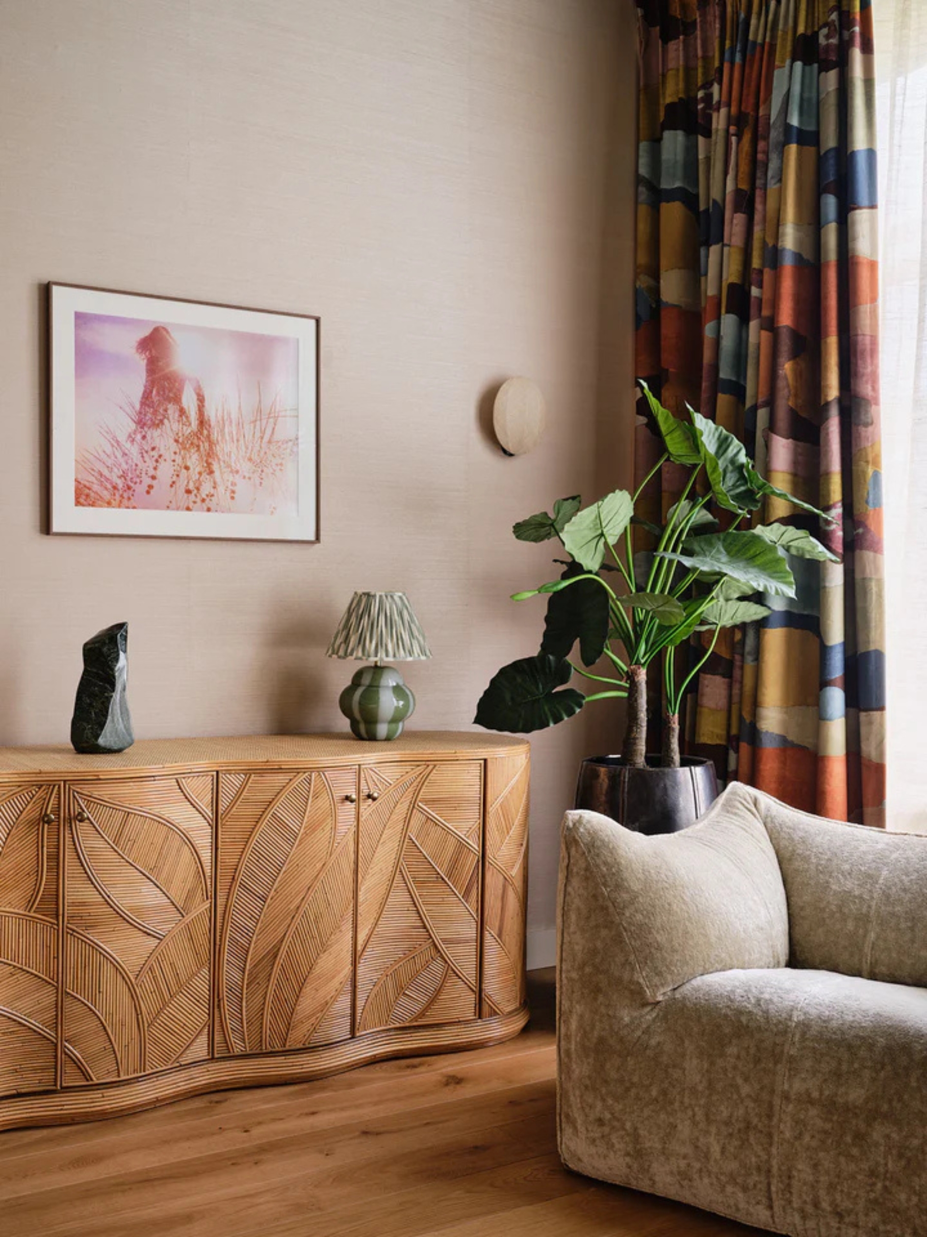 a bedroom with a decorative wicker cabinet and velvet couch, with a large potted plant in the corner