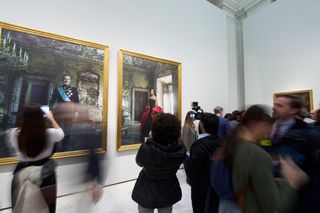 Tourists taking photos of Queen Letizia and King Felipe's new portraits hanging on a wall