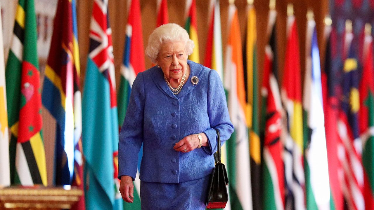 In this undated image released on March 6, 2021, Queen Elizabeth II walks past Commonwealth flags in St George&#039;s Hall at Windsor Castle, to mark Commonwealth Day, in Windsor, England.