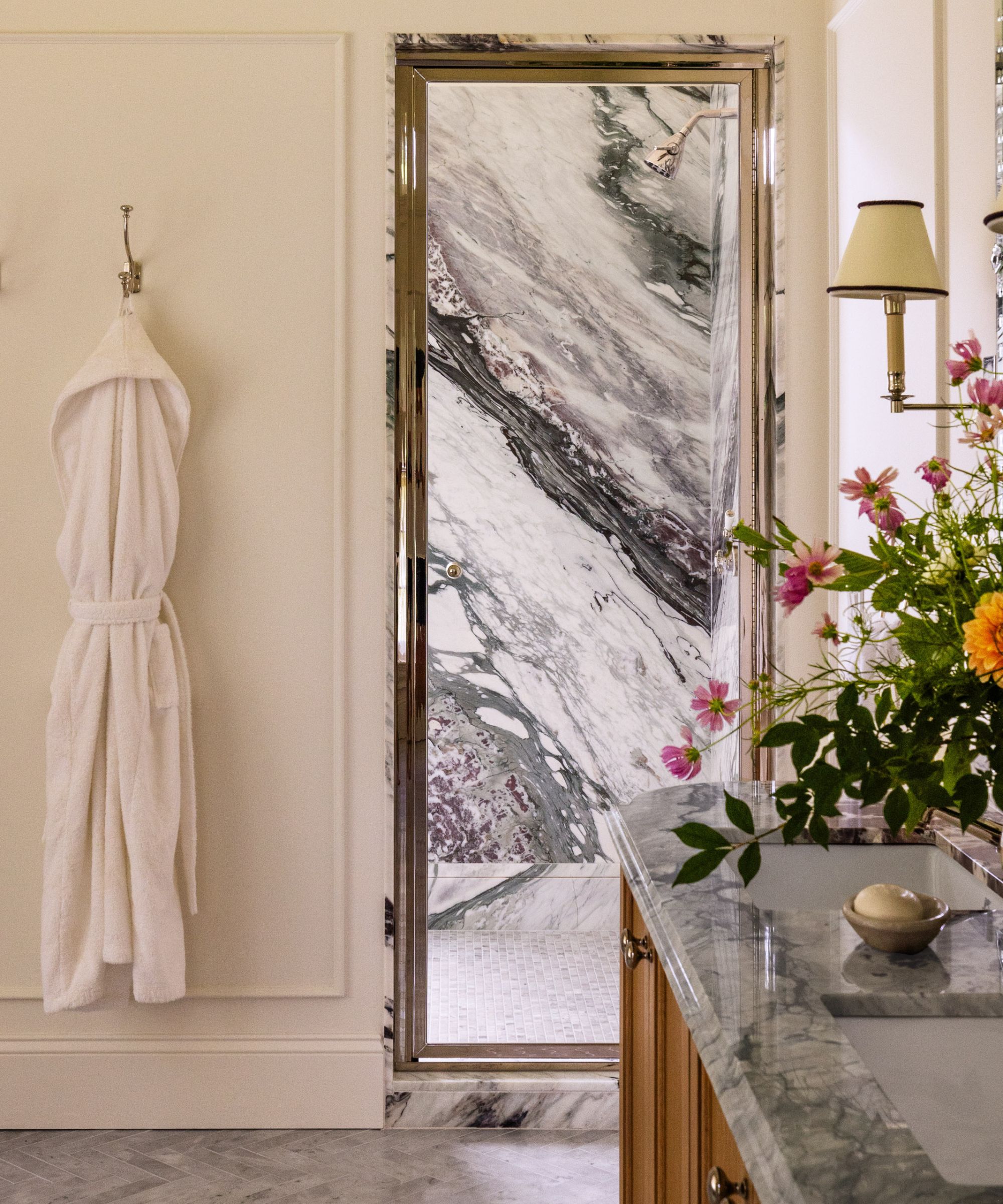 Marble bathroom with shower and countertops and wall sconces