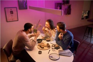 Philips Hue Ensis henger over et bord med mennesker som spiser.