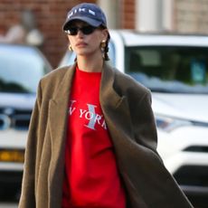 Hailey Bieber wearing a red sweater and camel coat in new york city