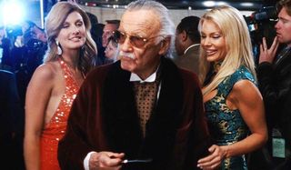 Iron Man Stan Lee, dressed as Hugh Hefner, with two beautiful models