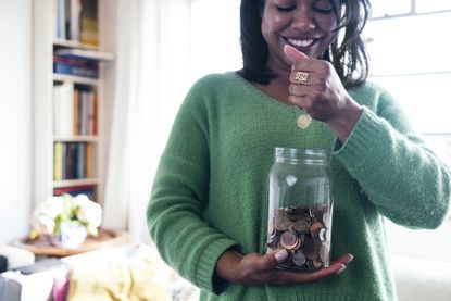 A woman holds a jar with cash in which represents a Lifetime ISA (image: Getty Images)