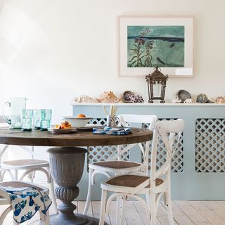Blue radiator cover with seashell on top, in kitchen which table and chairs