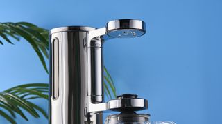 a silver drip brew coffee maker with a 10 cup capacity is photographed against a blue background