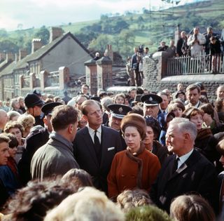 Queen Elizabeth and Prince Philip standing in a huge crowd of people in Aberfan, Wales in 1966