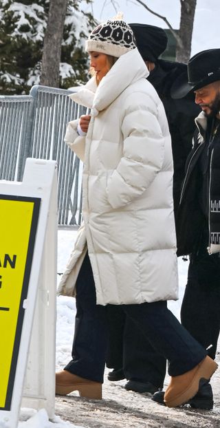 Jennifer Lopez wearing heeled UGG boots, white puffer coat and winter hat