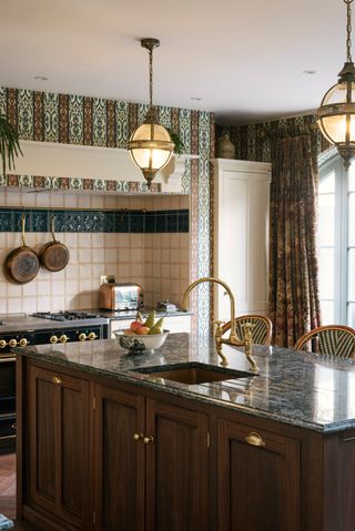 A dark mahogany wood kitchen island with a sink, large range cooker and curtains in a DeVol kitchen