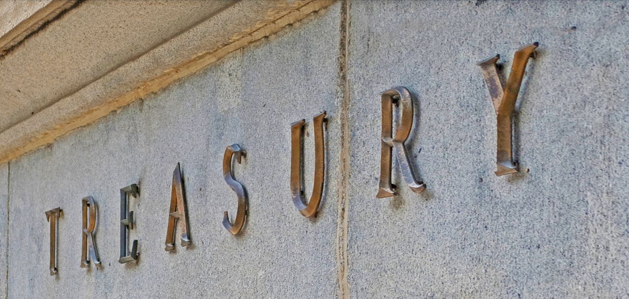 The word &quot;treasury&quot; spelled out in brass letters on marble, likely at the Treasury Department.