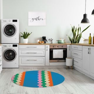 A multi-colored round kitchen rug sits in the middle of a gray kitchen