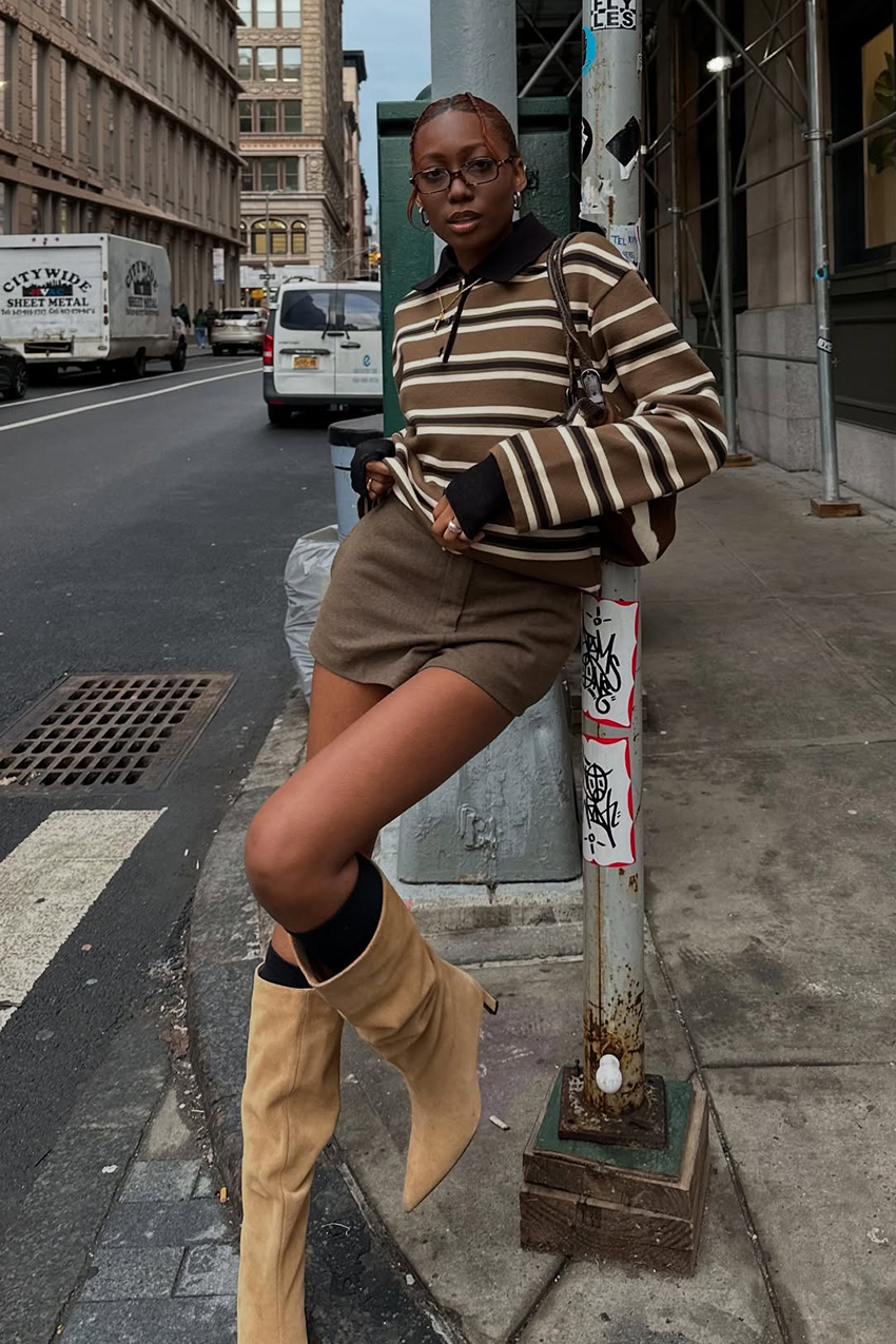 a woman wearing a striped long sleeve shirt, brown skirt, and slouchy tan boots