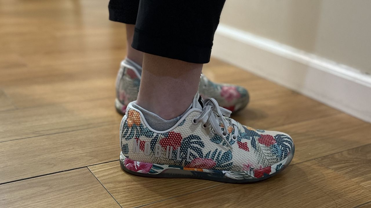 NoBull Outwork training shoes with tropical print resting on a wooden floor.