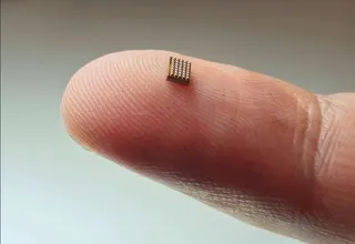 A tiny AI microchip sits on top of a finger.