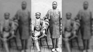 Here we see a black and white image of two Swahili women, one standing and one sitting, in stylish clothing.