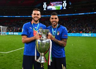 Rafael Toloi and Emerson Palmieri of Italy hold the Henri Delaunay Cup after Italy defeated England on penalties in the final of Euro 2020 at Wembley in London