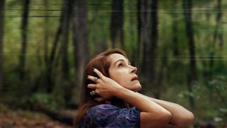 Julia Roberts clutching her head while standing in the woods during the Netflix movie Leave the World Behind.