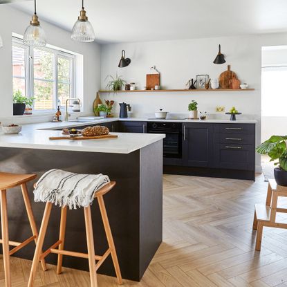 Open-plan kitchen-diner with blue units and peninsula island with bar stools