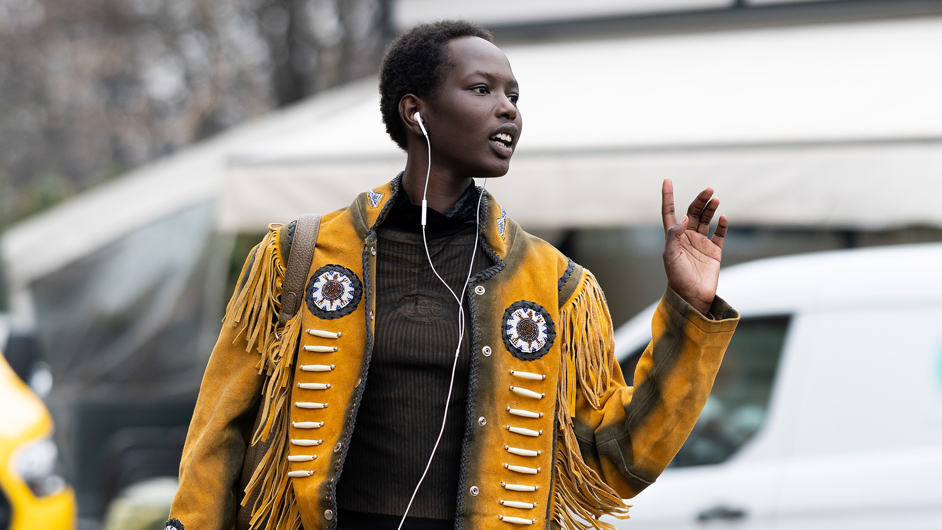 Woman wearing a yellow suede jacket with tassels.