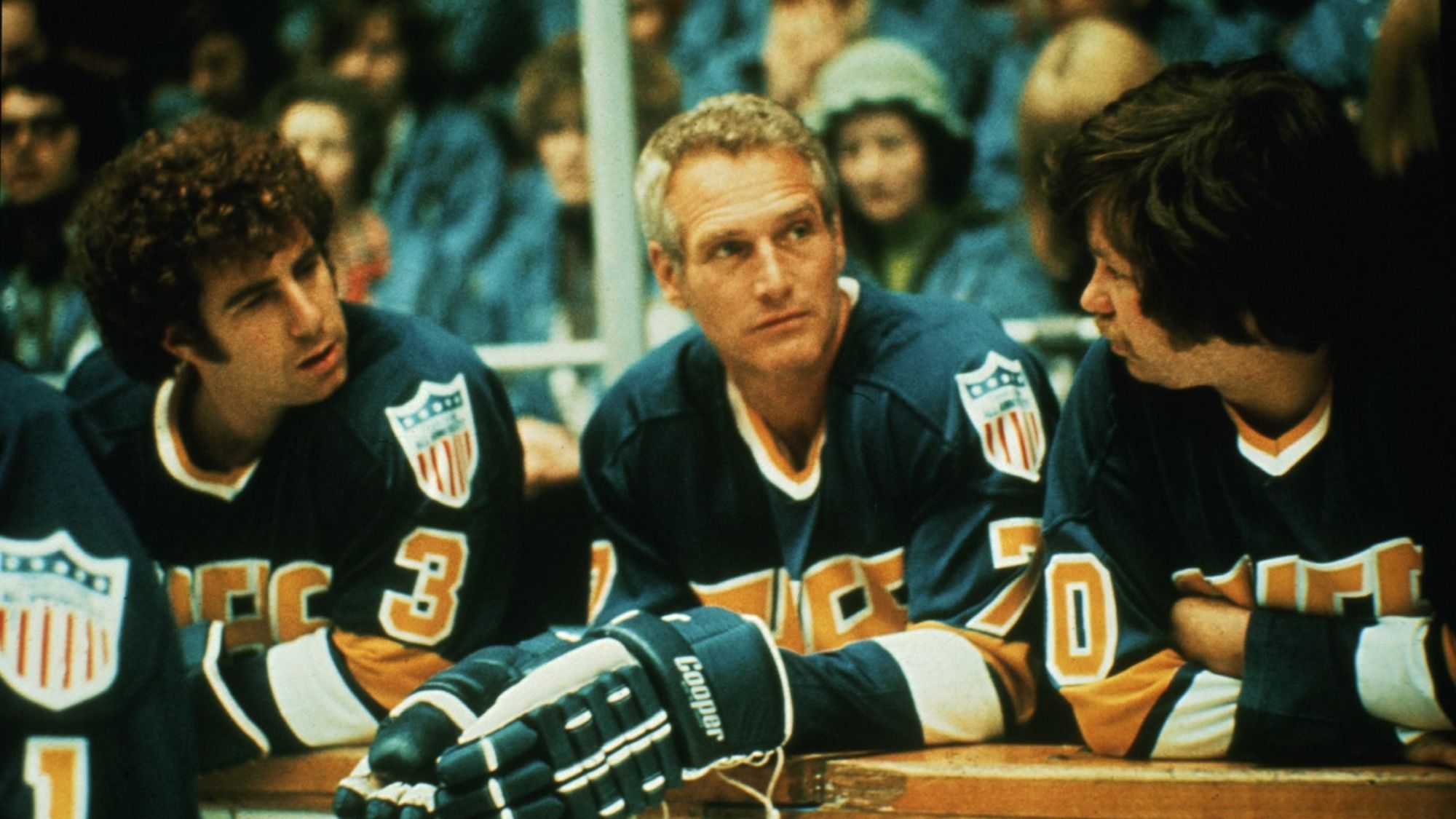 Paul Newman (center) in hockey gear behind the boards in Slap Shot