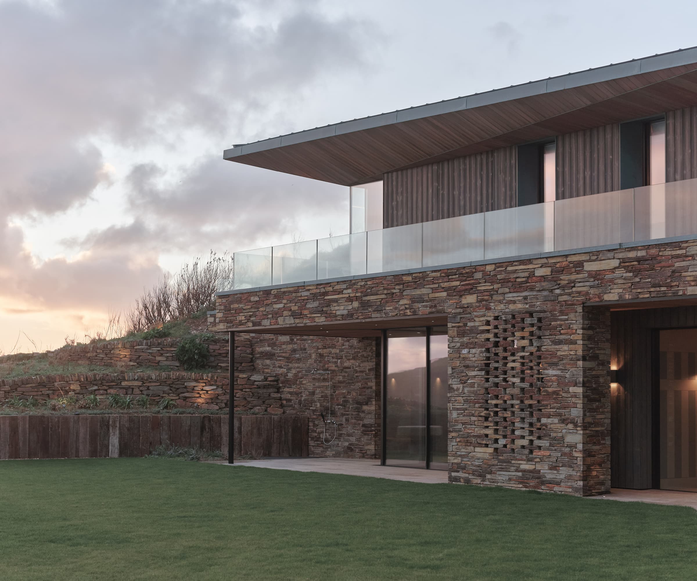 A stone house built into a Cornish cliff with a balcony