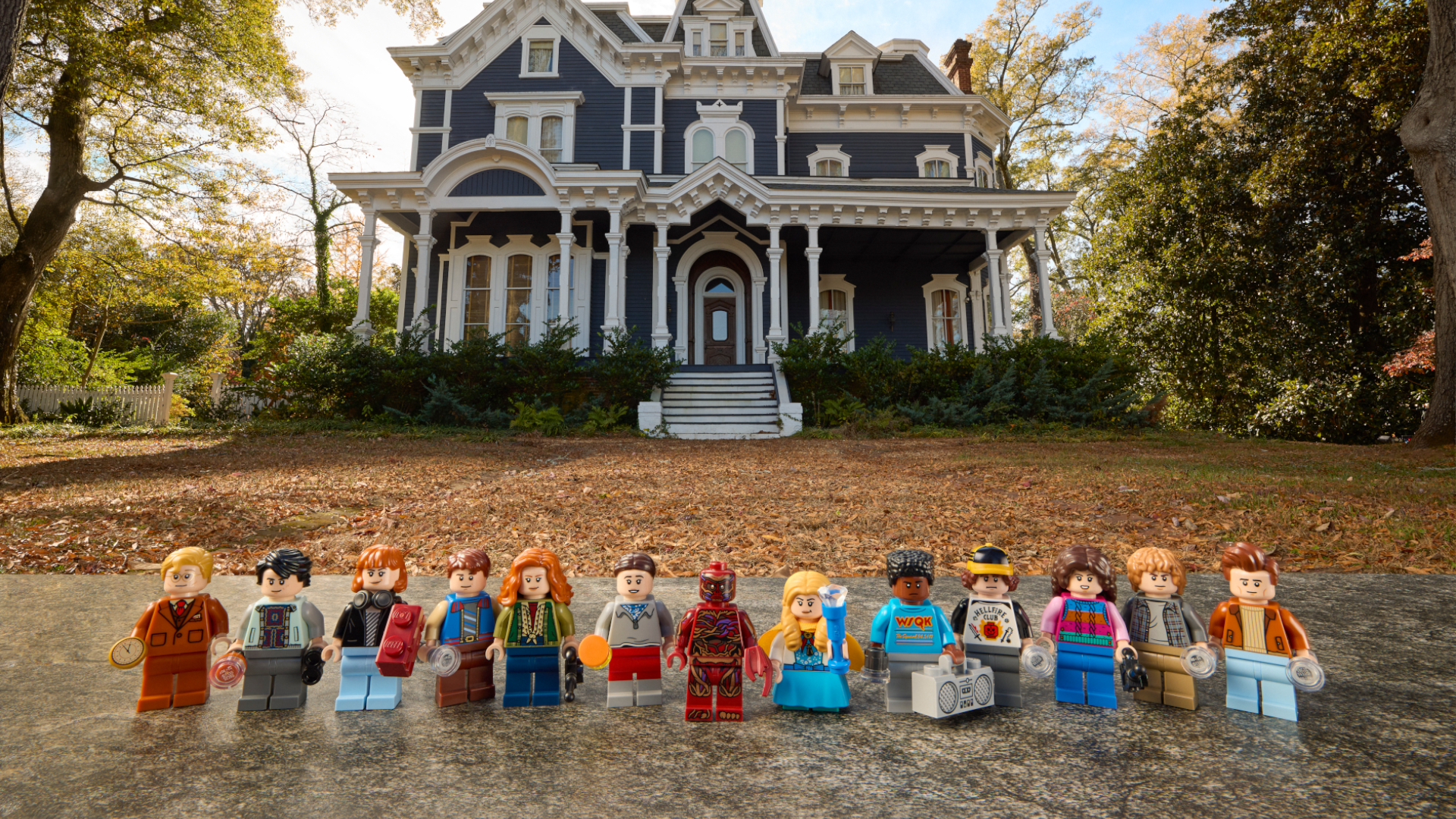 The Stranger Things Creel House minifigures stood in front of the real-life Creel House
