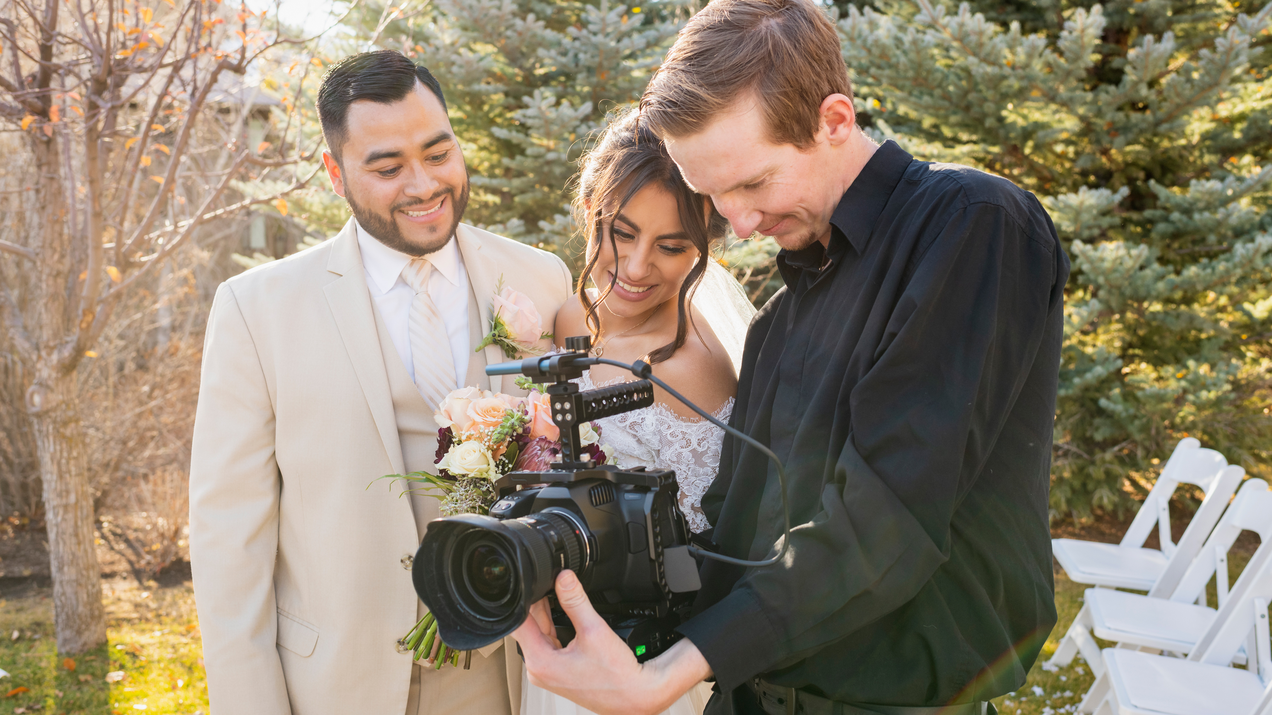 Bride and groom working with camera operator at outdoor wedding