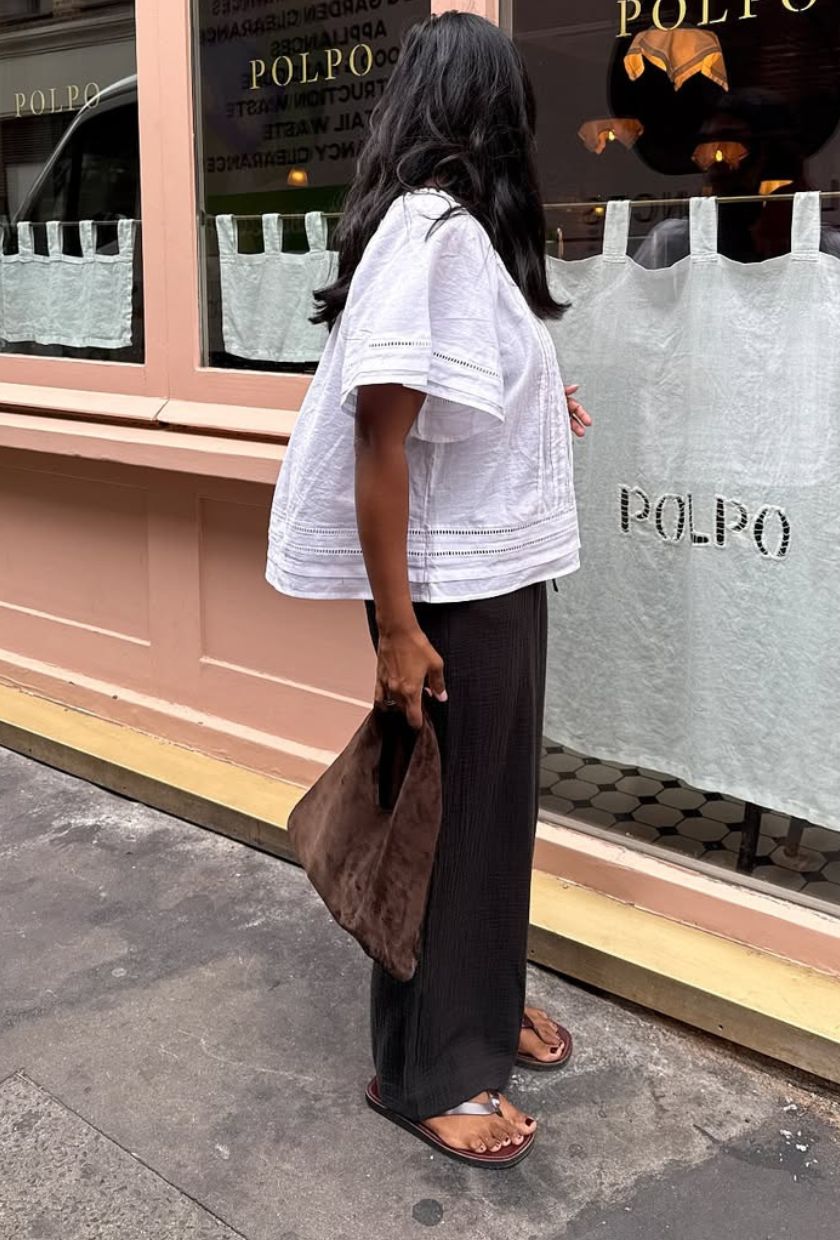 @monikh wears a slouchy suede bag from M&S with a white broderie top, black trousers and burgundy leather flip-flops