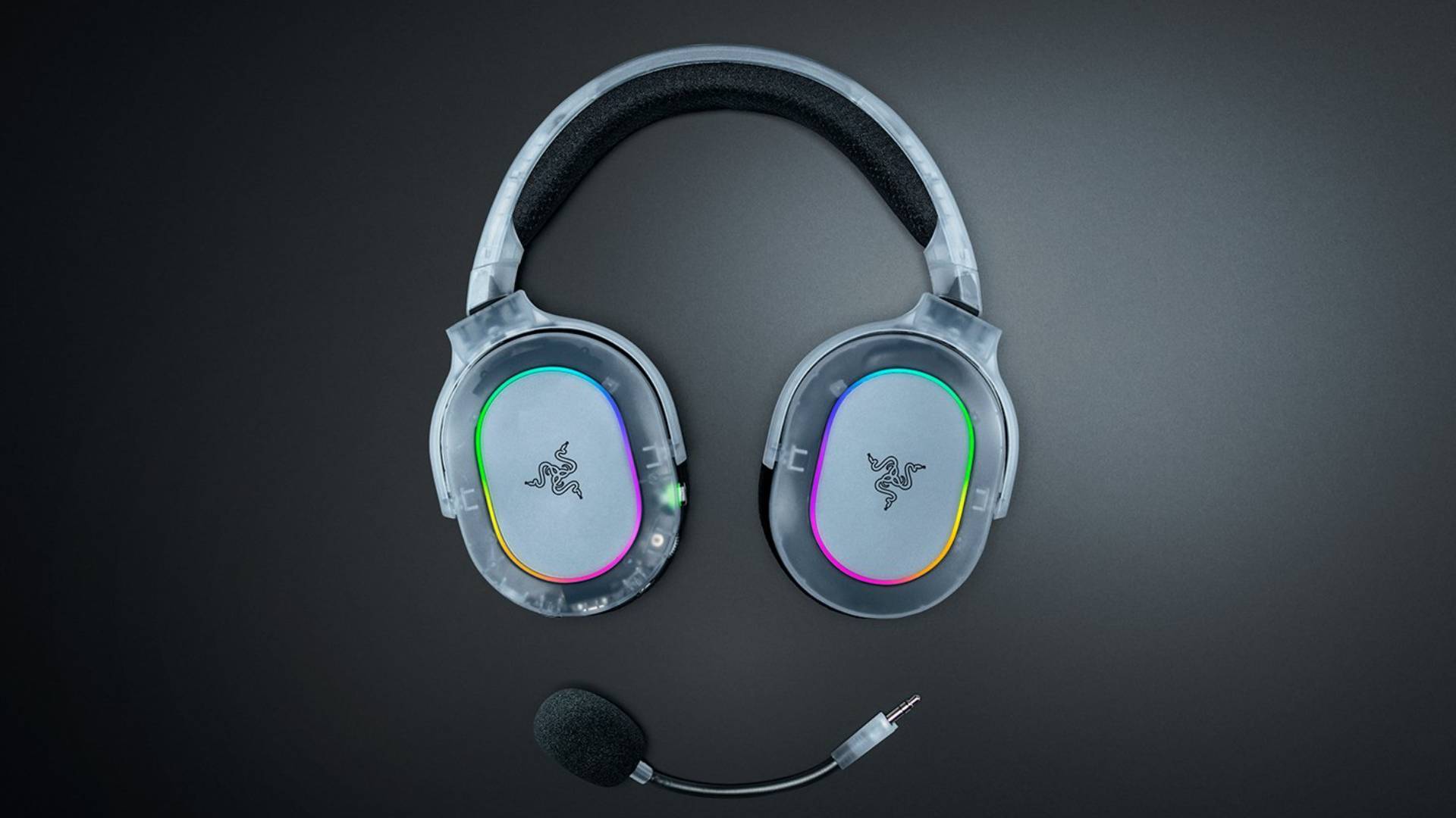 Promo image showing a translucent Razer headset and its detachable microphone sitting on a black table.