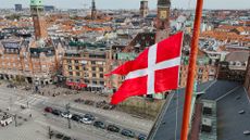 Aerial view of Copenhagen City Hall Square in Denmark, with Danish flag flying on pole in foreground.