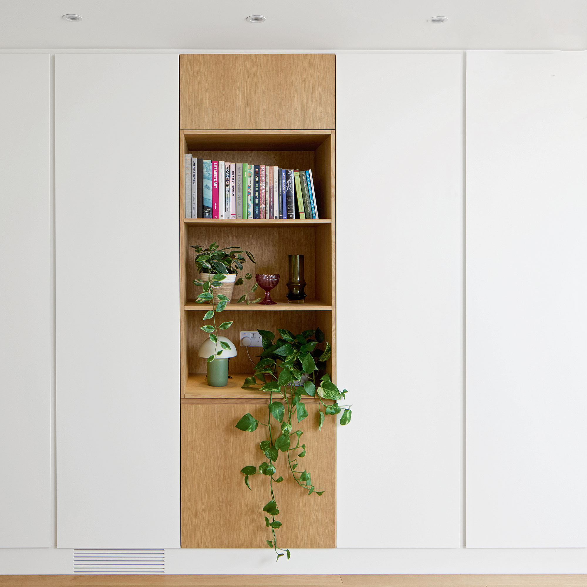 White and light wooden cabinetry with shelving filled with plants and books