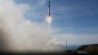 A black-and-white rocket launches into a blue sky