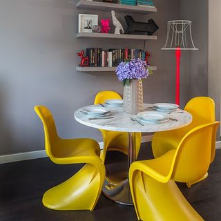 dinning area with grey wall wooden flooring and dinning table with yellow chairs