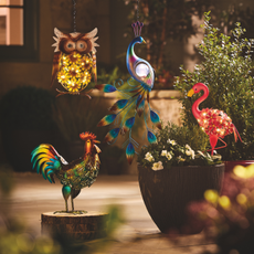 Solar rooster, flamingo, owl and peacock on a patio.