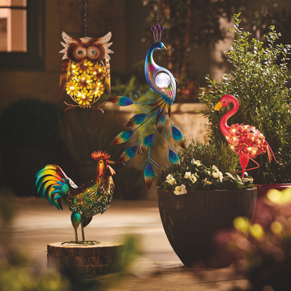 Solar rooster, flamingo, owl and peacock on a patio.