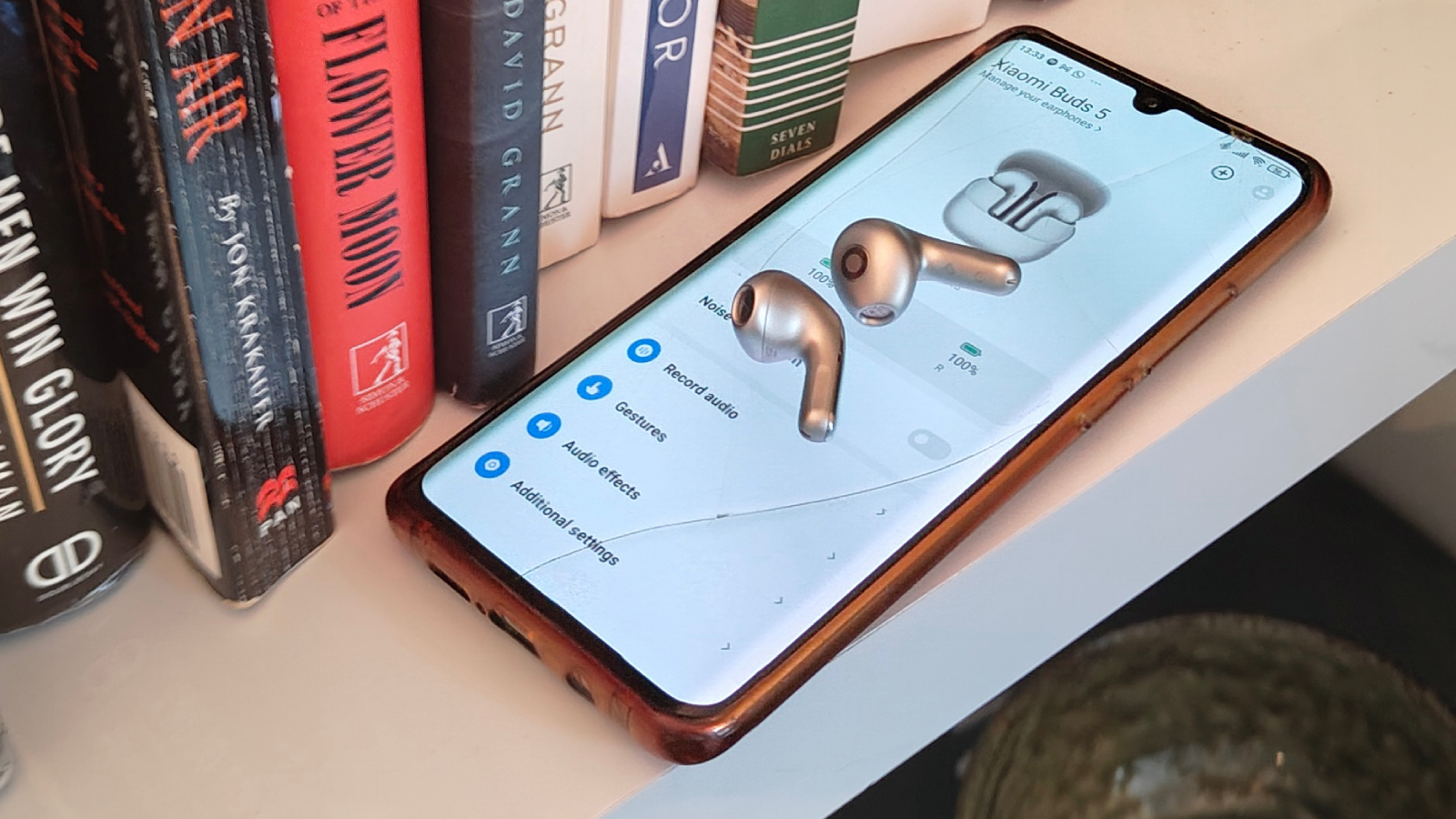 The Xiaomi Buds 5 on a bookshelf.