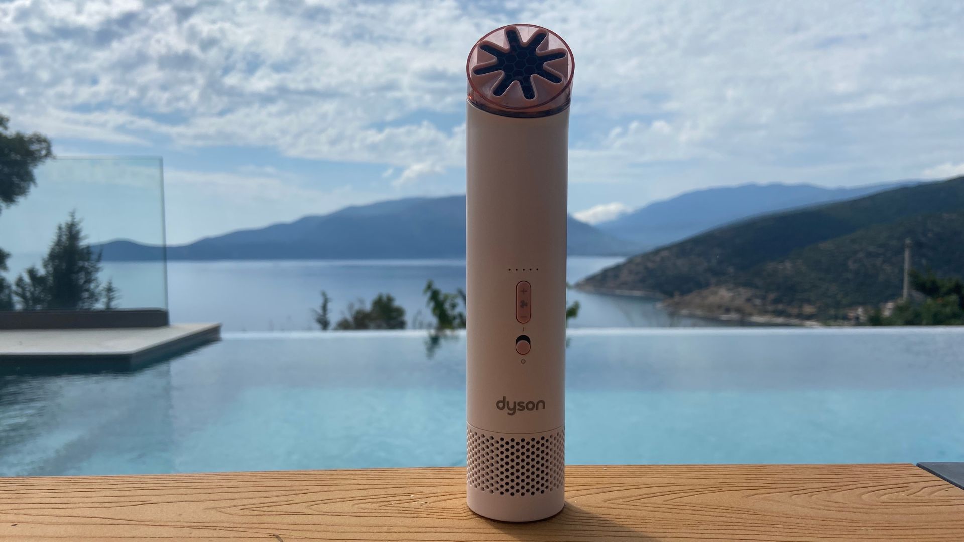 The Dyson HushJet Mini Cool Fan sat on a table in front of a pool