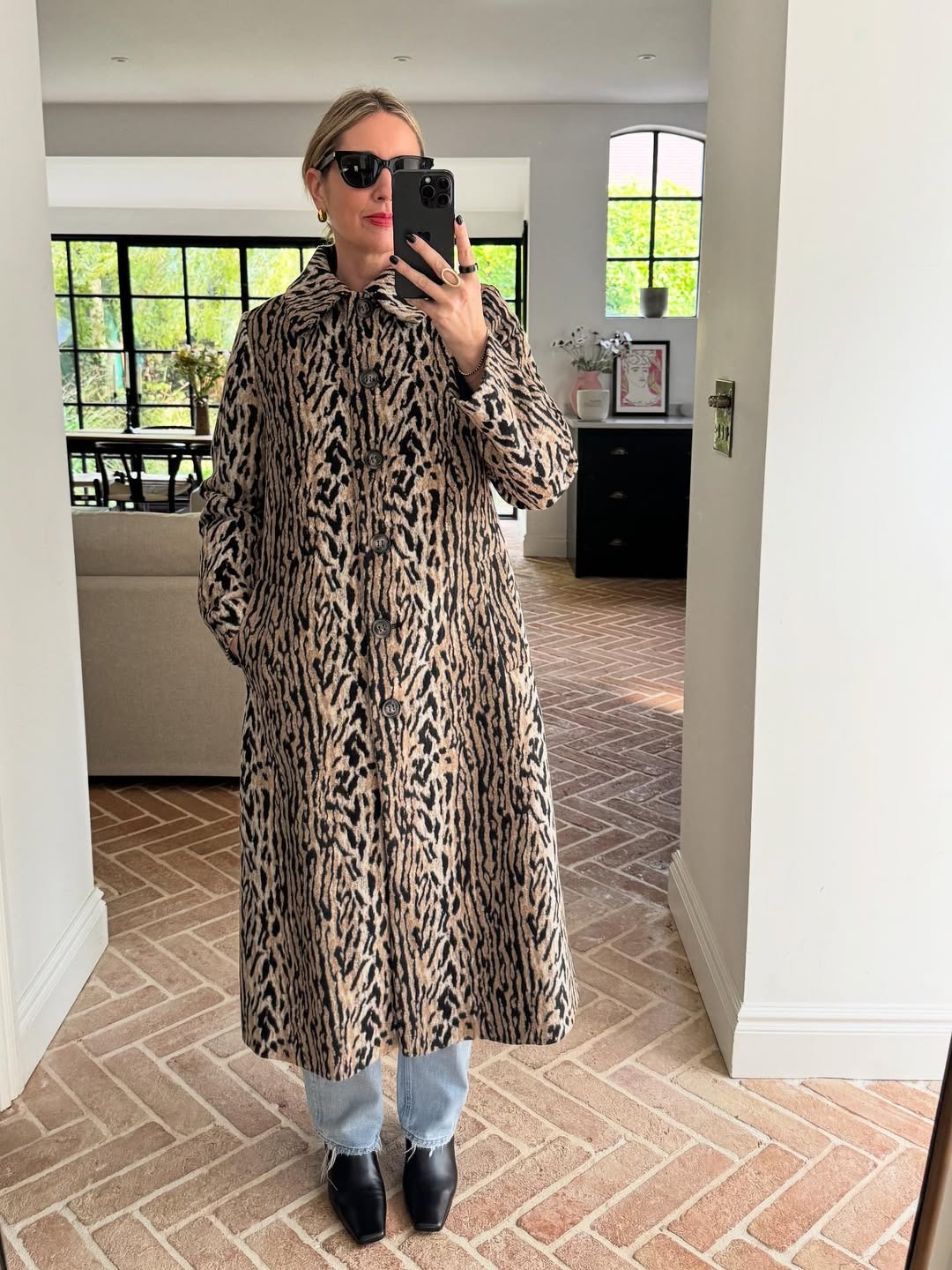 Woman wears leopard print coat with blue jeans and black boots